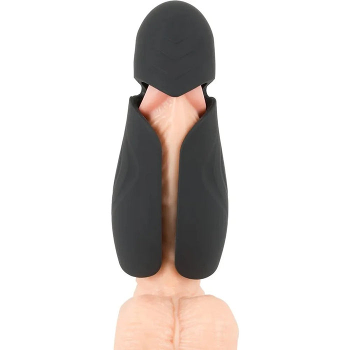 An erect penis inside the black masturbator with a hood over the tip of the penis and flaps that surround the shaft 