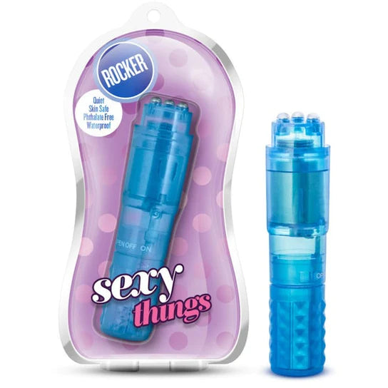 a blue clitoral vibrator with three silver balls on the flat top, shown next to its plastic packaging
