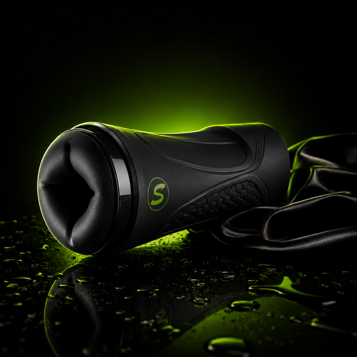 Black handheld adult wellness device with textured grip and soft-touch opening, photographed on a glossy surface with water droplets and dramatic neon green backlighting.