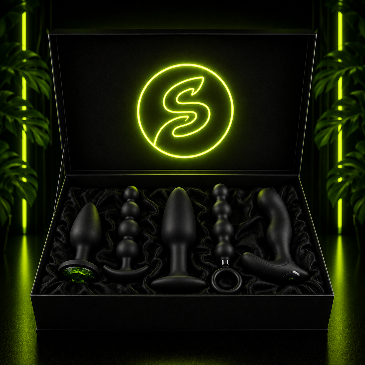 Open black display box lined with satin, featuring a neon green logo and a collection of black adult wellness products under dramatic green accent lighting.