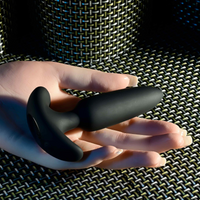 Black anal vibrating plug sizing example photo against hand.