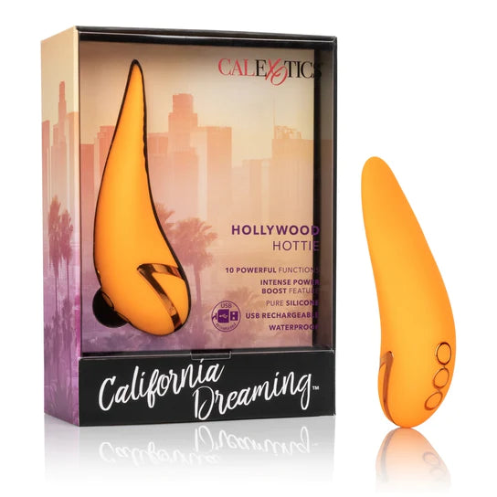 An orange tongue shaped vibrator with golden accents. It comes in a city scape box with a plastic cover