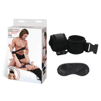 Black ankle cuffs and a black eye mask next to the product box which depicts a man kneeling beside a woman holding her bound feet in the air