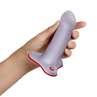 Hand holding a gray and red amor dildo device on a white background