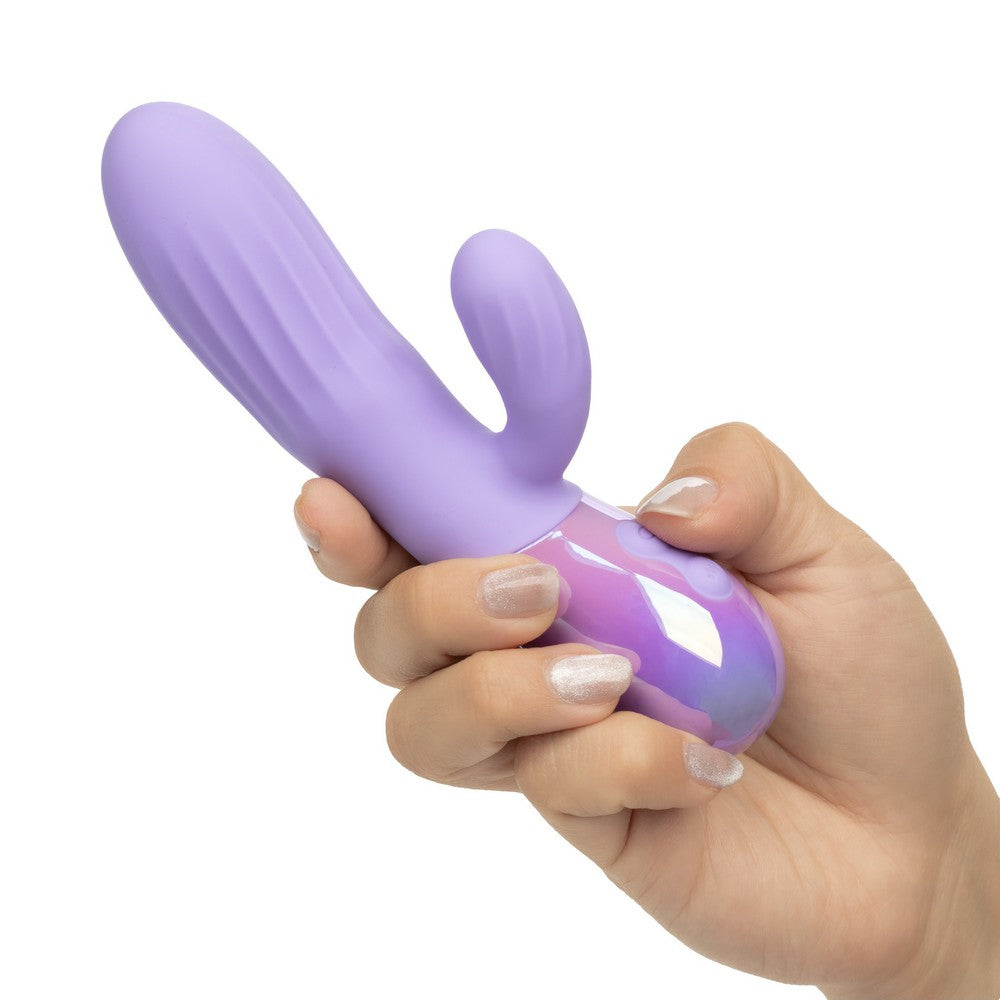 A hand holding a purple cactus-shaped personal massager with a glossy iridescent purple and pink base against a plain white background.