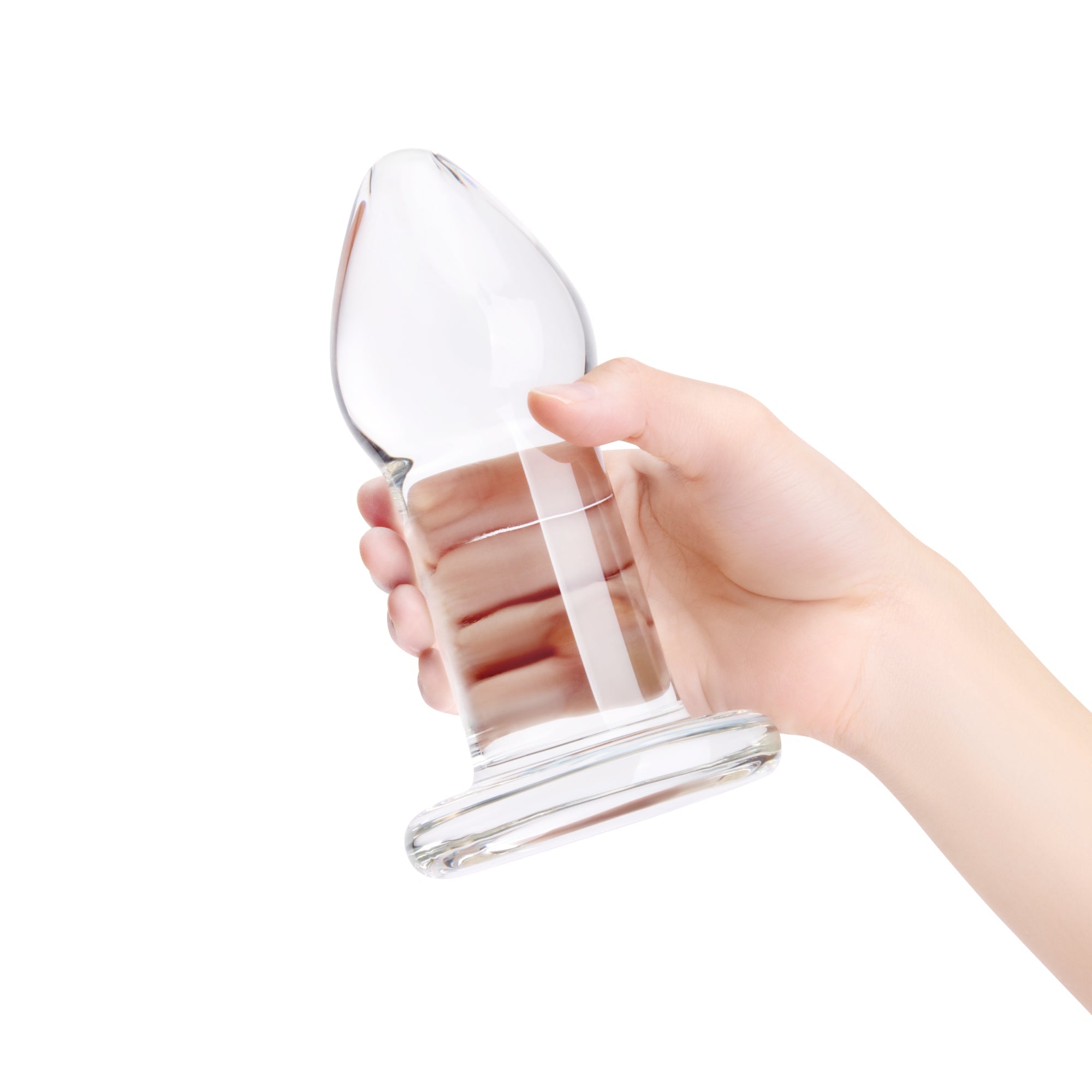 Clear glass anal plug held by a hand on a white background