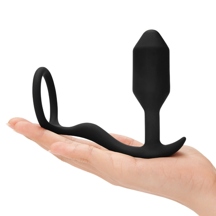 Black silicone butt plug held in a hand on a white background
