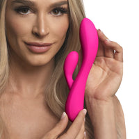 Woman holding a pink vibrator device against a white background