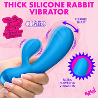A hand holds a bright blue rabbit-shaped vibrator against a pink promotional background with text reading 'THICK SILICONE RABBIT VIBRATOR,' 'FLEXIBLE SHAFT,' '3 SPEEDS,' 'PATTERNS OF VIBRATION,' and 'ULTRA POWERFUL VIBRATION.'.