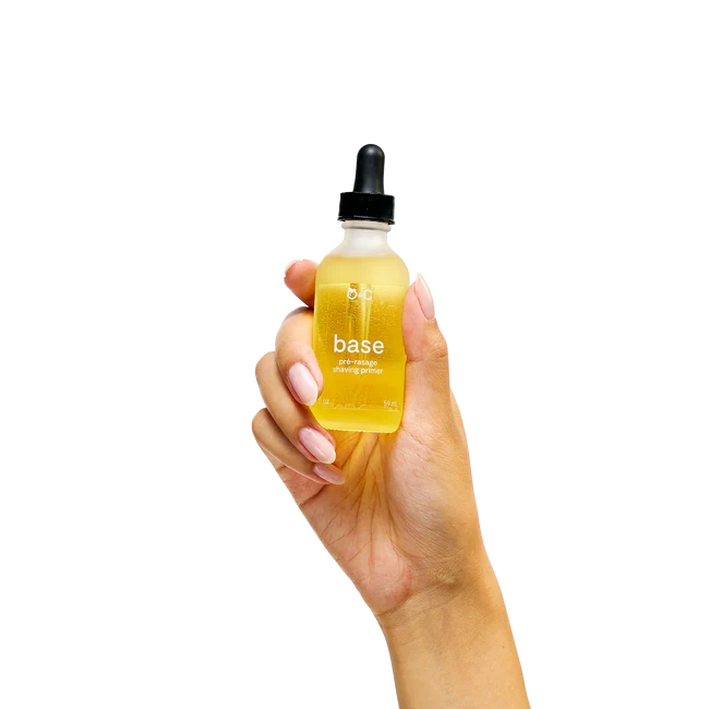Hand holding a bottle labeled 'base' with a dropper on a white background