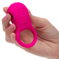 Hand holding a Pink rechargeable ridge rider cock ring against a white background