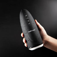 Hand holding a black Bathmate product against a dark background