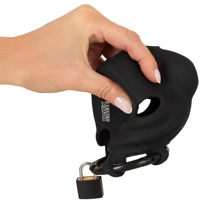 Black velvets cock & ball Cage with lock held by a hand on a white background