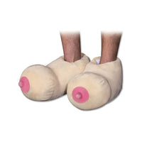 A pair of beige-colored slippers designed to resemble playful bosoms with pink accents.