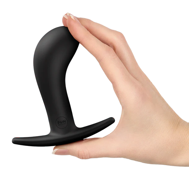 Black silicone anal plug held in a hand on a white background