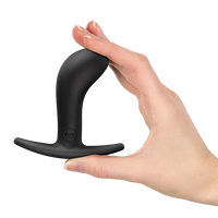 Black curved anal plug held in a hand against a white background
