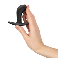 Black curved anal plug held in a hand against a white background