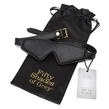 a black face mask with gold buckles sitting on top of its black storage bag