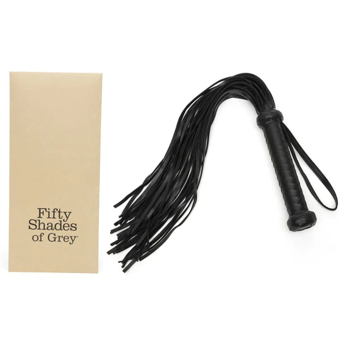 a black flogger with a black wrist strap shown next to its beige packaging
