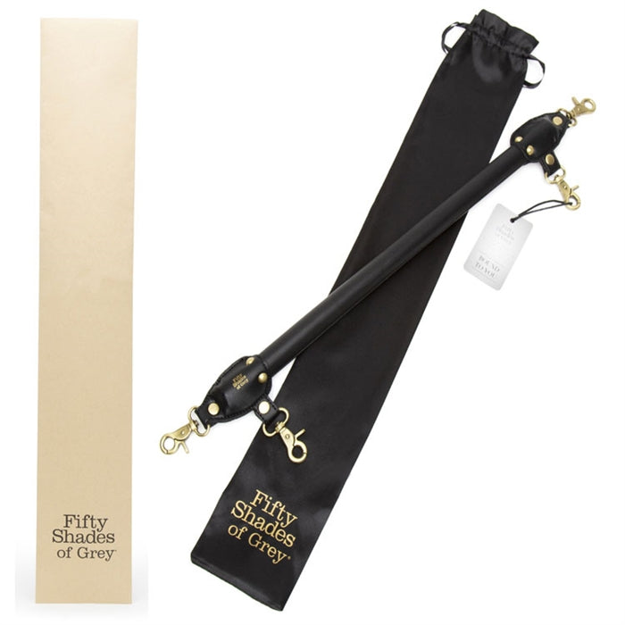 Black spreader bar with gold clasps laying in front of black storage bag