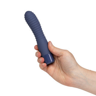 A hand holding a dark blue ribbed personal massager against a plain white background.