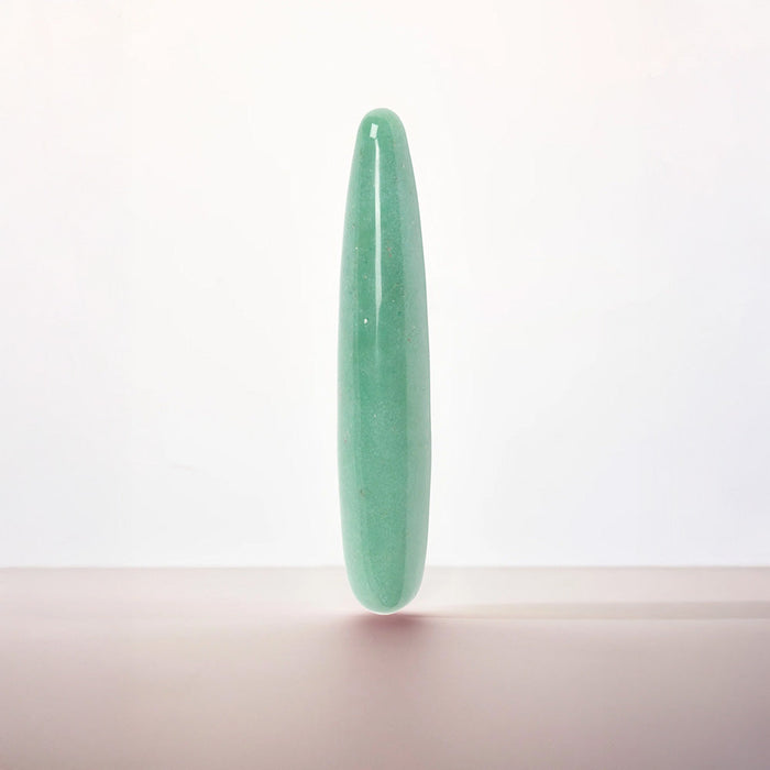 A polished light green jadeite cylindrical wand or crystal pointer standing upright on a neutral surface against a clean white background.