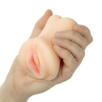 A flesh-toned silicone maturbator toy being held and squeezed by a hand against a plain white background.