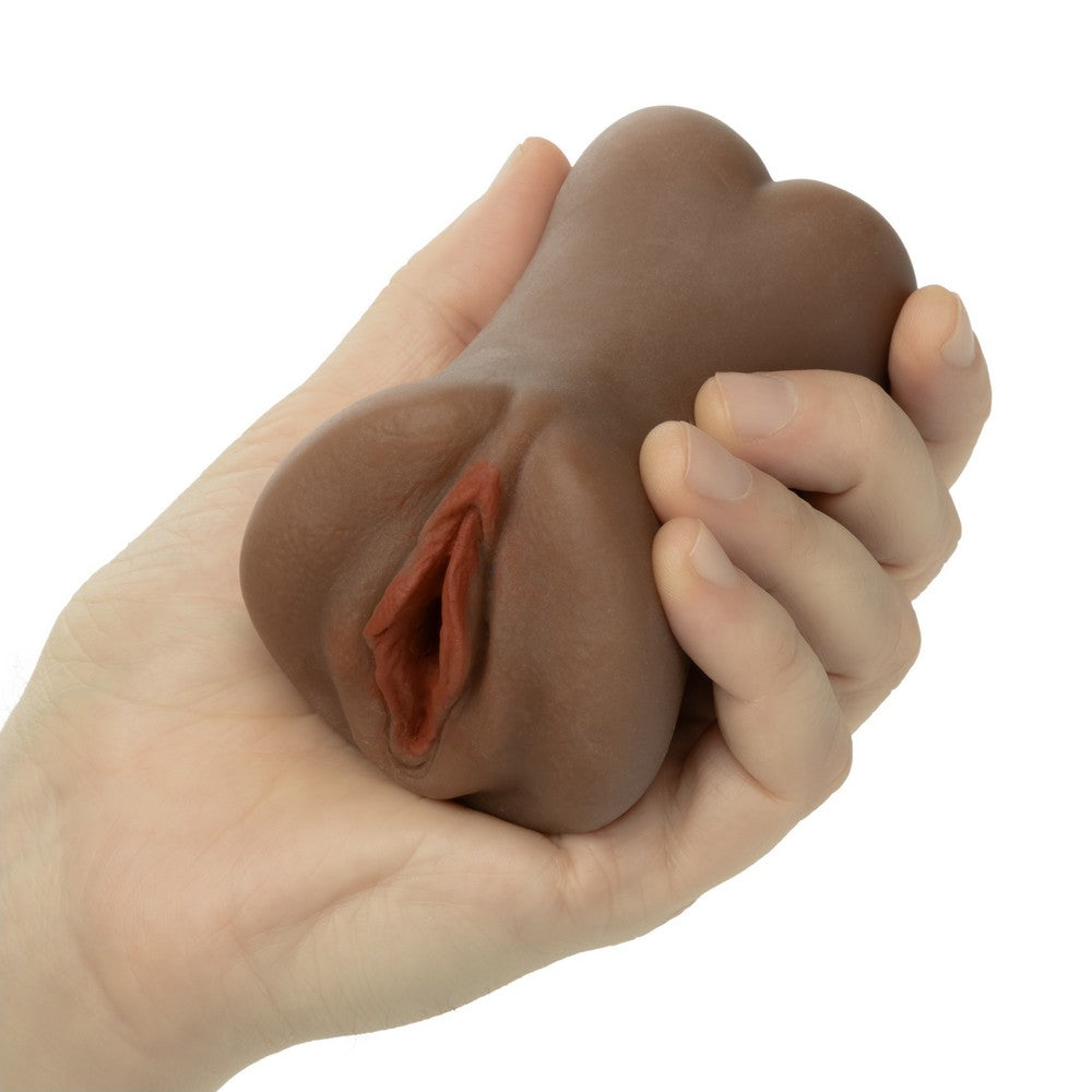 A hand holding a realistic brown silicone adult novelty toy against a plain white background.