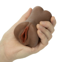 A hand holding a realistic brown silicone adult novelty toy against a plain white background.