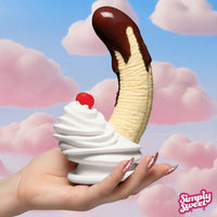 banada split with chocolate sauce and cherry on top dildo held by a hand against a cloud-themed background with 'Simply Sweet' branding.