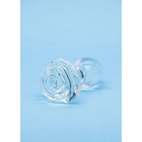 A clear glass butt plug with textured rose-shaped ends and smooth round bases, displayed on a light blue background.