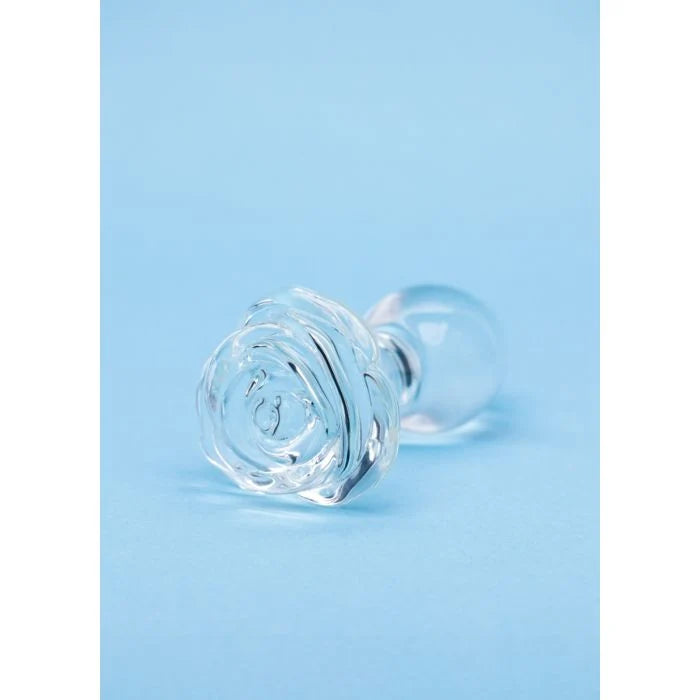 A clear glass butt plug with textured rose-shaped ends and smooth round bases, displayed on a light blue background.
