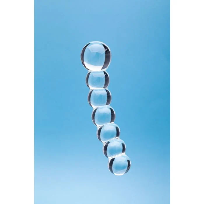 A clear glass or acrylic segmented rod or stand made of seven stacked transparent spheres, shown against a solid light blue background.
