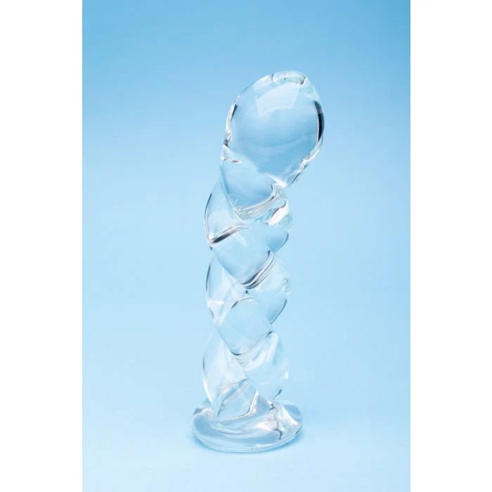 A clear glass spiral dildo standing upright on a light blue background.