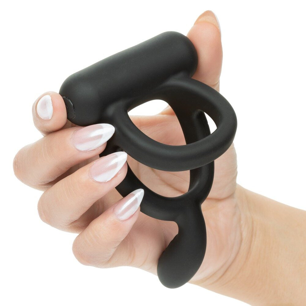 Black closer caress cock ring held in a hand with white nail polish on a white background