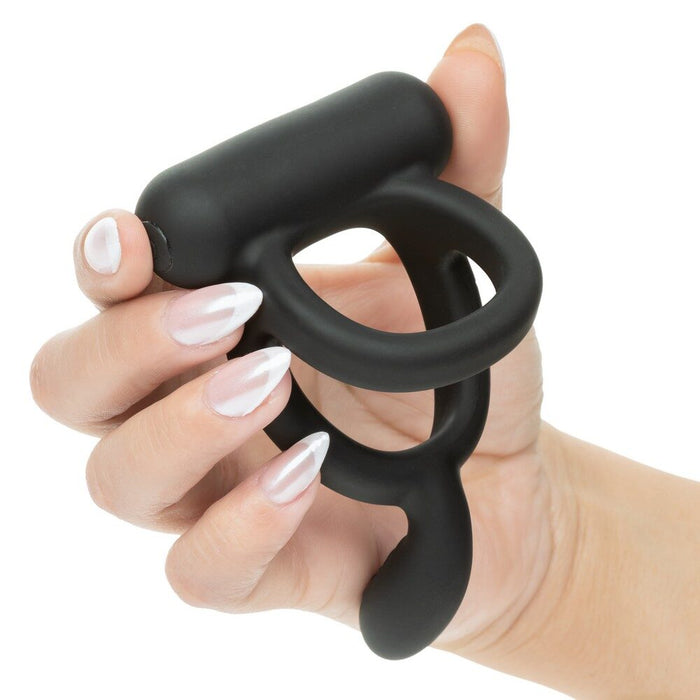 Black closer caress cock ring held in a hand with white nail polish on a white background