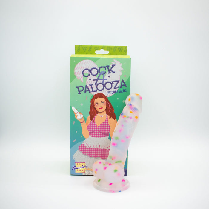 Silicone dildo with colorful sprinkles next to its packaging on a white background