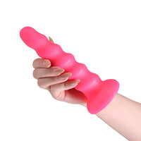 A bright pink silicone twisted didlo being held by a person's hand against a plain white background.