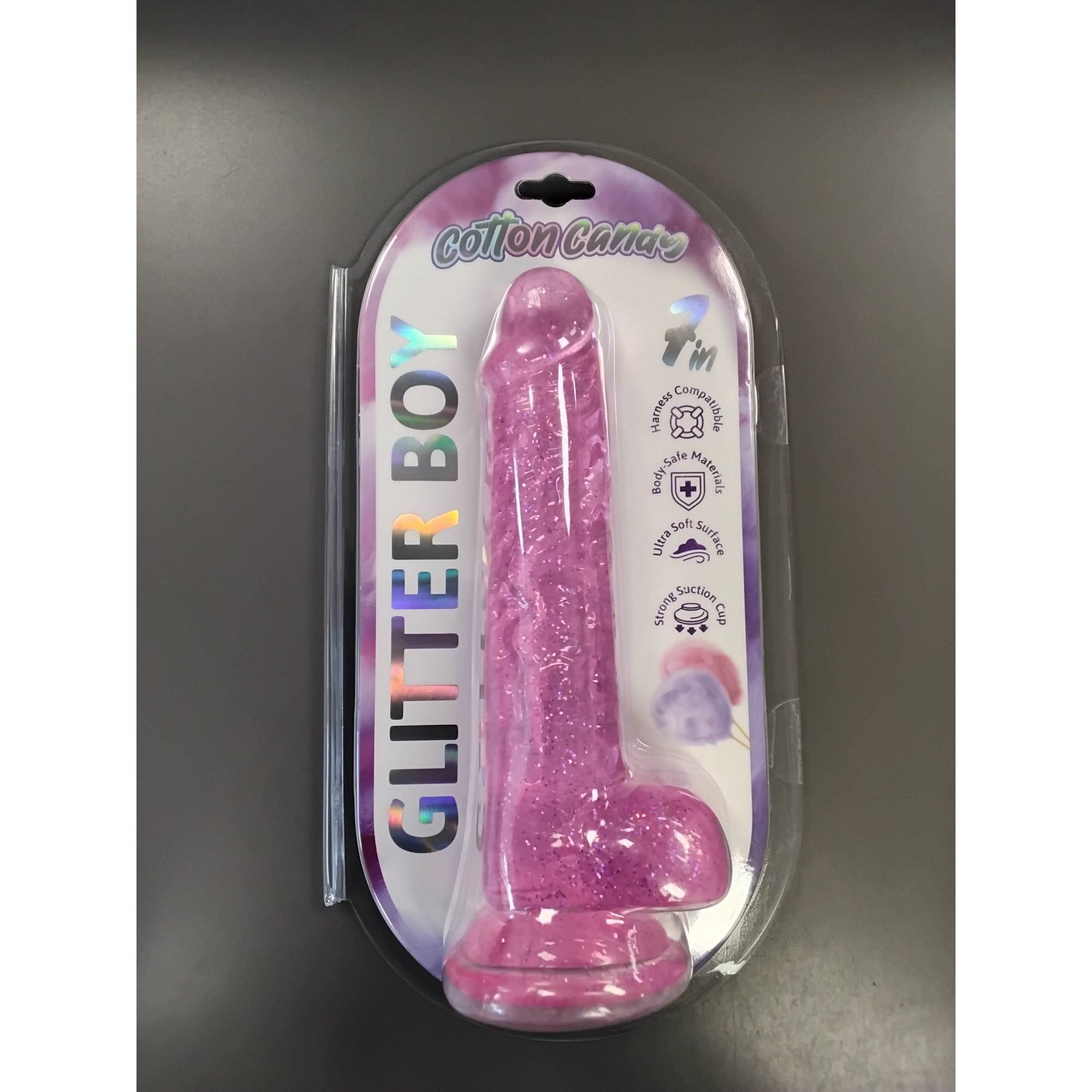 A packaged pink glitter novelty dildo labeled 'GLITTER BOY' and 'Cotton Candy' on a dark gray background.