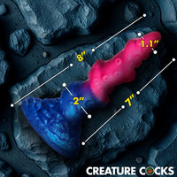Measurement chart of a blue and pink creature cock on a dark textured background with 'Creature Cocks' branding.