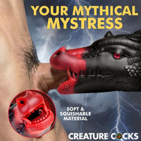Promotional graphic for a black and red dragon-shaped adult novelty toy being inserted into a person's penis, with lightning background, large yellow text reading 'YOUR MYTHICAL MYSTRESS,' a circular inset close-up of the red mouth area, and the brand name Creature Cocks at the bottom.