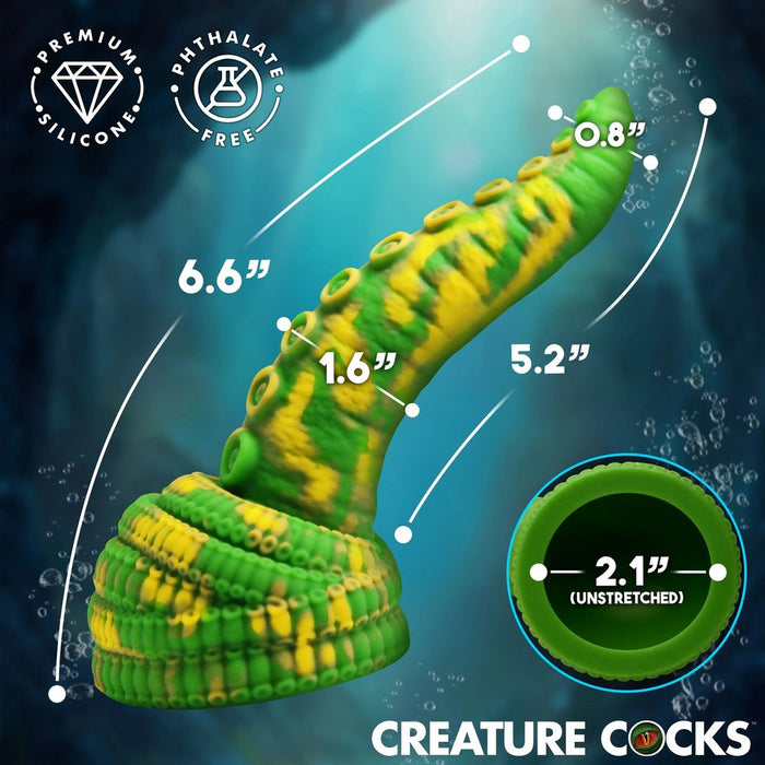 A green and yellow striped silicone crab claw toy for aquariums, shown with dimension lines indicating stretched and unstretched measurements, on a dark blue underwater-themed background.