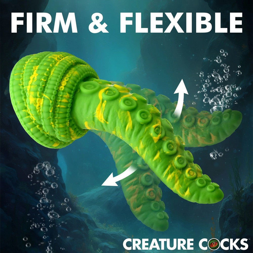 A green and yellow novelty product with suction cup details, shown underwater with white arrows and the text 'FIRM & FLEXIBLE' and 'CREATURE COCKS'.