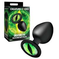 Black silicone butt plug with green eye design on packaging, on a white background