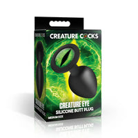 black tapered butt plug, with green eye on base, on box packaging