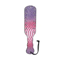 A paddle-style strap-on accessory with a textured reptile-skin pattern in a purple-to-pink gradient, featuring small metallic studs and a black wrist strap, shown on a plain white background.