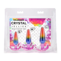 Packaged set of rainbow-colored 'Crystal Jellies' anal trainer products by Doc Johnson on a colorful geometric patterned background.