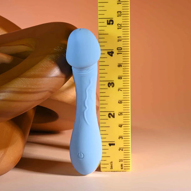 Selopa Dainty Dick vibrator  with a yellow measuring tape for scale on a peach background