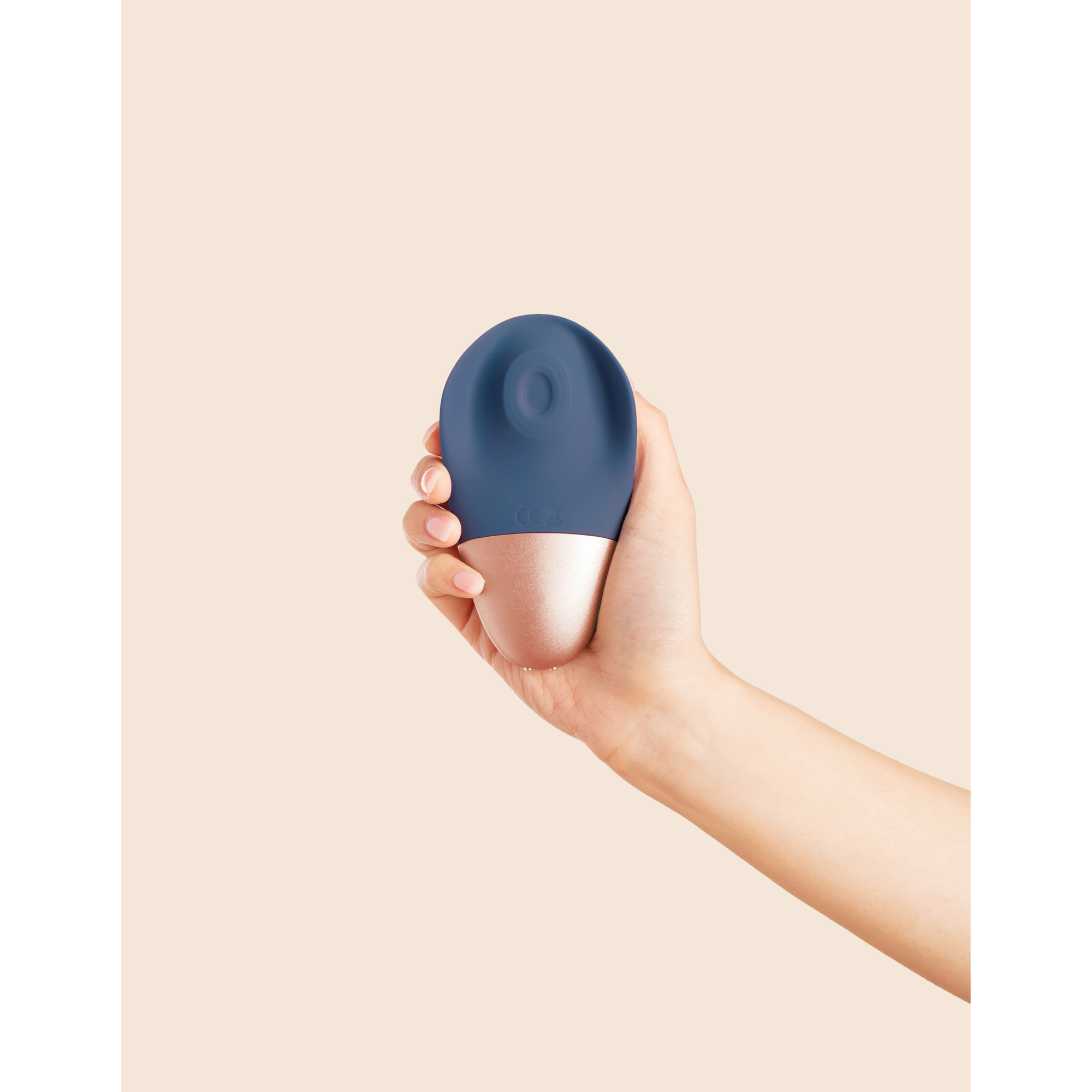 navy and rose gold hand held massager, held in a hand