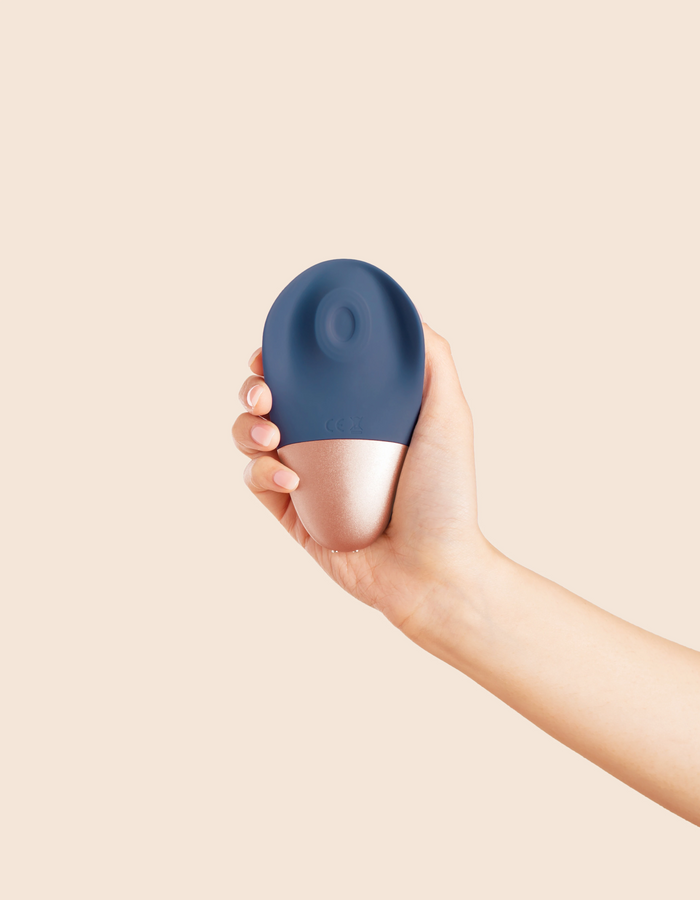 navy and rose gold hand held massager, held in a hand